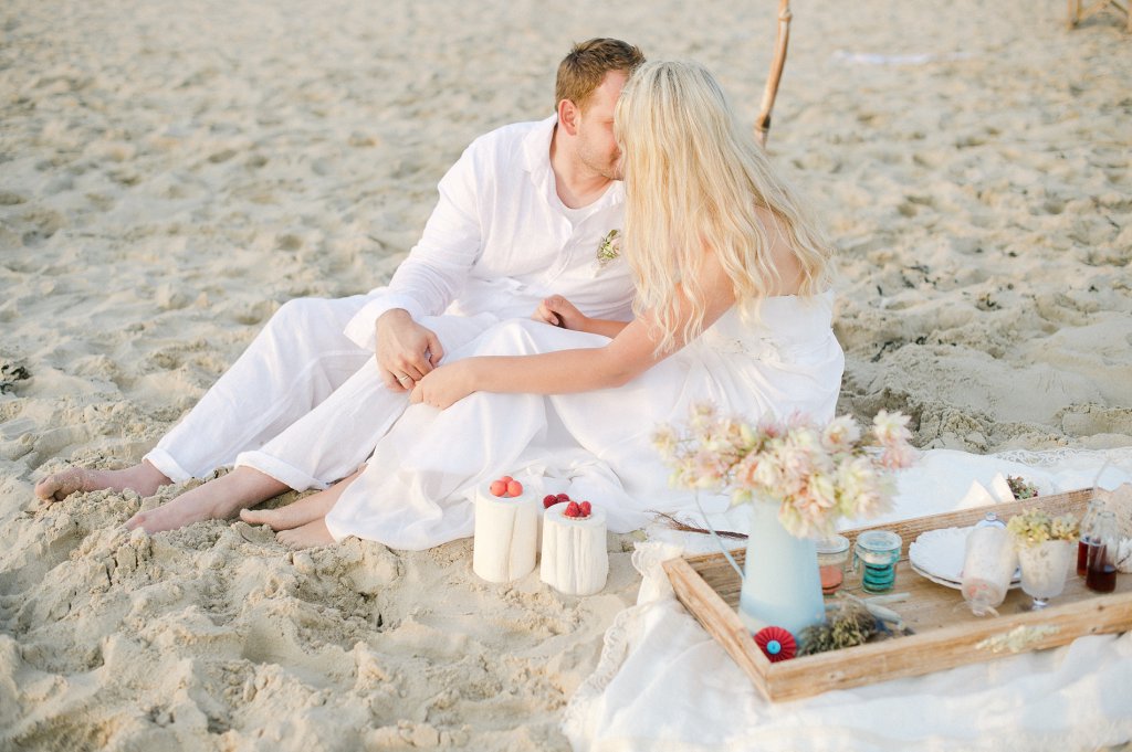 Photo Brautpaar am Strand beim Picknick, küssend